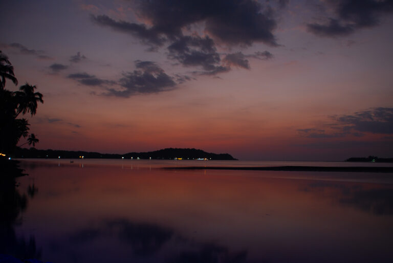 A bay at sunset in Siolim, Goa, in Southern India is pictured here. The photograph was originally clicked by Yuvan Kumar and can be categorised as travel photography, minimalism. The colours are pink, orange.