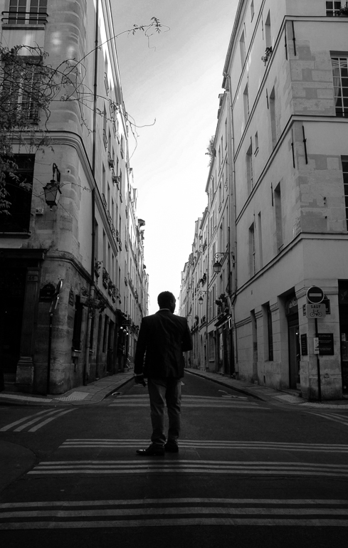A black and white photo of a man at a crossroads in Paris.